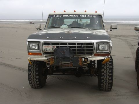 1991 Ford Bronco - A modified Ford Bronco sits on a sandy beach with another vehicle partially visible to the right.