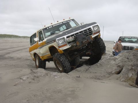 1991 Ford Bronco - Two Ford Broncos on a beach, one is actively navigating sandy terrain.