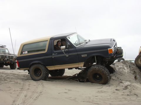 1991 Ford Bronco - Ford Bronco navigating a sandy incline with a second vehicle nearby.