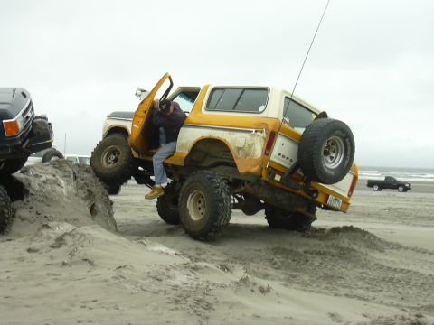 1991 Ford Bronco - This lifted Ford Bronco is navigating a sandy terrain with another vehicle visible in the background.