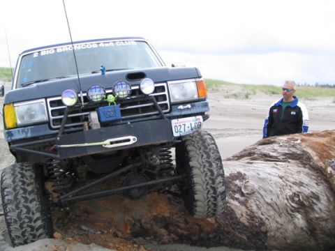 1991 Ford Bronco - Modified 1991 Ford Bronco navigating a beach, with a man standing nearby.
