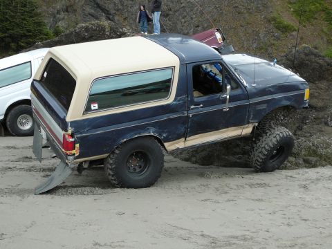 1991 Ford Bronco - This Ford Bronco is navigating a sandy beach with other vehicles nearby.