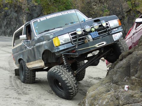 1991 Ford Bronco - A modified 1991 Ford Bronco navigates a rocky beach, its off-road capabilities.