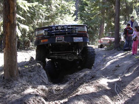 1991 Ford Bronco - Modified 1991 Ford Bronco tackling a challenging off-road obstacle with spectators nearby.