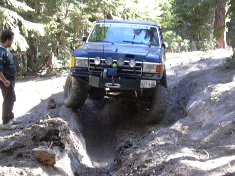 1991 Ford Bronco - This Ford Bronco is navigating a challenging off-road trail with steep inclines and rough terrain.
