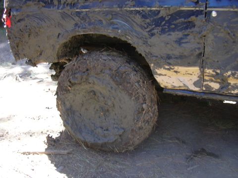 1991 Ford Bronco - A heavily mud-covered vehicle tire and fender are visible from the side, suggesting off-road use.