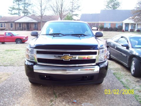 2008 Chevrolet Silverado 1500 - A black 2008 Chevrolet Silverado 1500 is parked in a driveway, with a red truck and a black coupe visible in the background.