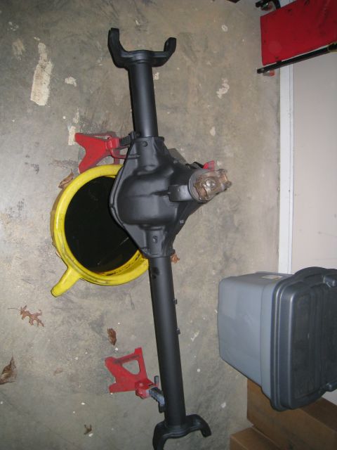 1996 Ford Bronco - Differential axle assembly supported by red jack stands, with a yellow oil drain pan nearby.