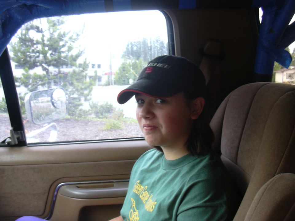 Young person in black cap and green shirt seated in a vehicle