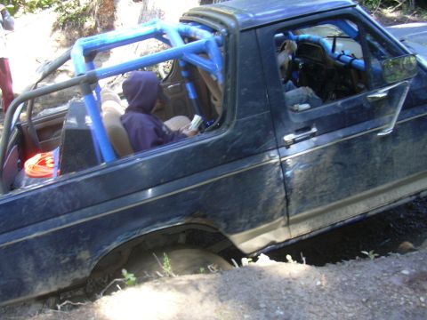 1991 Ford Bronco - Off-road vehicle with custom roll cage navigates difficult terrain, getting stuck in mud.