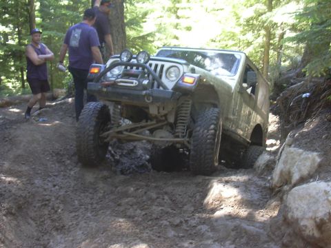 1991 Ford Bronco - A Jeep Wrangler TJ tackles a challenging off-road course, with onlookers observing the difficult maneuver.
