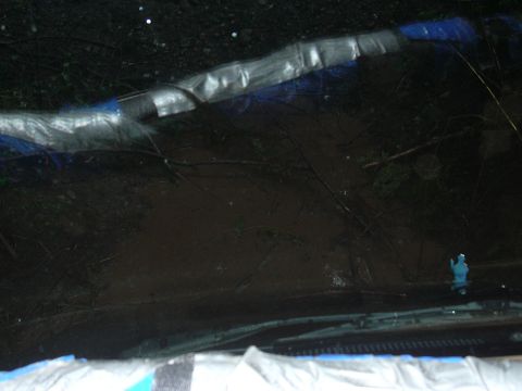 1991 Ford Bronco - Looking through the windshield, the dashboard is covered in tape and branches are visible outside.