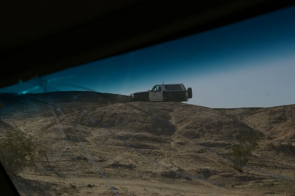 Two-tone SUV with a spare tire on the rear, parked on a dusty hill