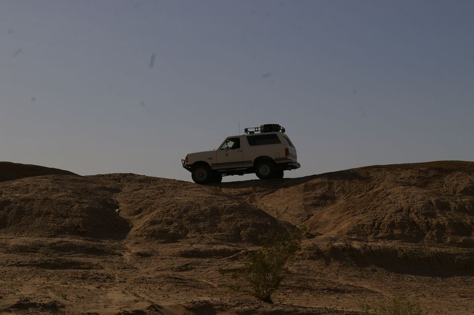 White 1986 Ford Bronco on dirt hill with roof rack