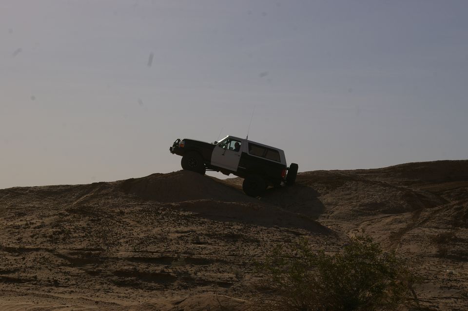 SUV climbing sand dune, side view