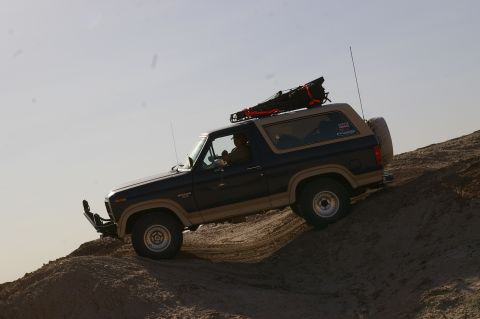 1986 Ford Bronco - This two-tone Ford Bronco is navigating a sandy incline with a loaded roof rack.