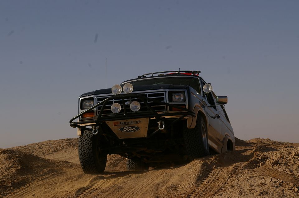 Ford Bronco driving on sand dunes with aftermarket bumper and lights