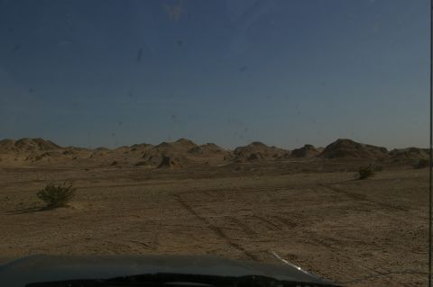 1986 Ford Bronco - View of a desert landscape with mountains in the distance and tire tracks on the sandy ground.