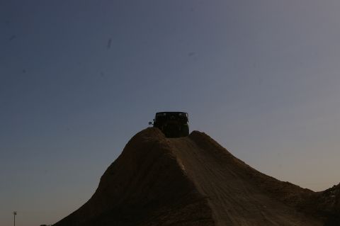 1986 Ford Bronco - A dark SUV is silhouetted on a dirt mound under a clear sky.