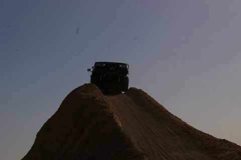 1986 Ford Bronco - A 1986 Ford Bronco navigates a steep dirt incline, silhouetted against the sky.