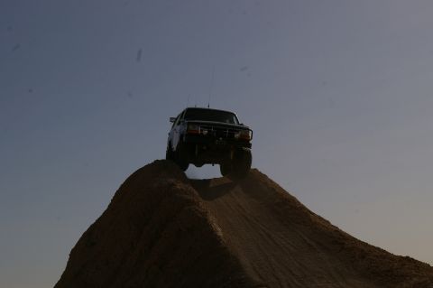 1986 Ford Bronco - 1987 Ford F-150 cresting a dirt hill during an off-road excursion.