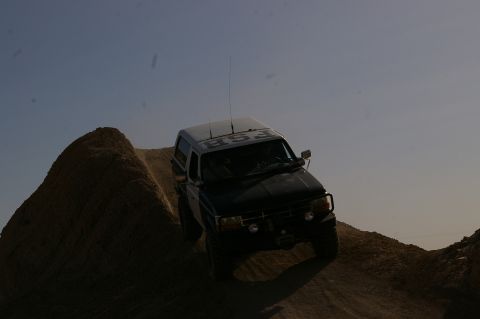1986 Ford Bronco - Ford Bronco navigates an off-road obstacle, showing its off-road capabilities.