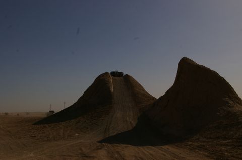 1986 Ford Bronco - An SUV is captured cresting a large dirt mound under a clear sky, its off-road capabilities.