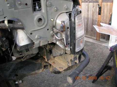 1996 Ford Bronco - The front end of a vehicle shows significant damage, with exposed mechanical components and a detached bumper bracket.