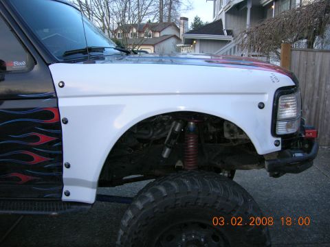 1996 Ford Bronco - Close-up of a 1996 Ford Bronco's front fender, showing custom flames and suspension.