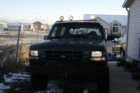 1994 Ford Bronco - A dark-colored Ford Bronco is parked in a driveway with a second vehicle visible to the right.