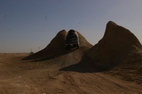 1986 Ford Bronco - Van navigates challenging terrain in a dry, arid environment under a clear sky.