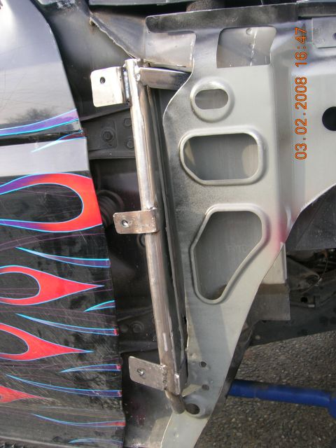 1996 Ford Bronco - Close-up of a custom metal bracket attached to a vehicle's frame, with flame graphics visible on the adjacent door panel.