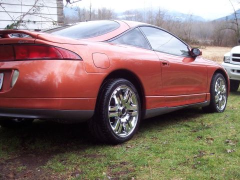 1995 Mitsubishi Eclipse - Rear view of an orange 1995 Mitsubishi Eclipse with custom wheels, parked outdoors.