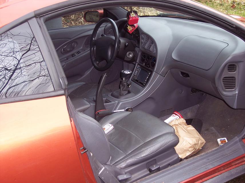 Interior shot of a 1995 Mitsubishi Eclipse, showing the dashboard, seats, and center console
