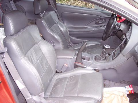 1995 Mitsubishi Eclipse - The interior of a car is shown, leather seats and a manual shifter. A watermark is visible in the lower right corner.