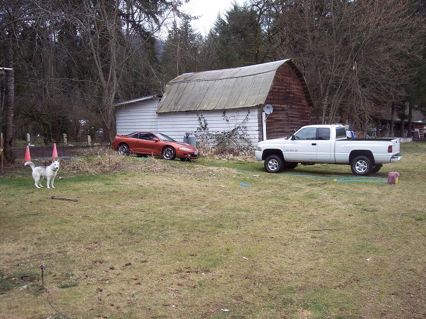 Orange sports car, 3q-front view. A white pickup truck is also visible