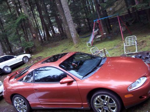 1995 Mitsubishi Eclipse - Orange 1995 Mitsubishi Eclipse coupe with a sunroof sits in a yard with a playground in the background.