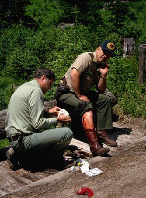 1974 Ford Ranchero - A park ranger provides first aid to a colleague with a severe leg injury in a wooded area.