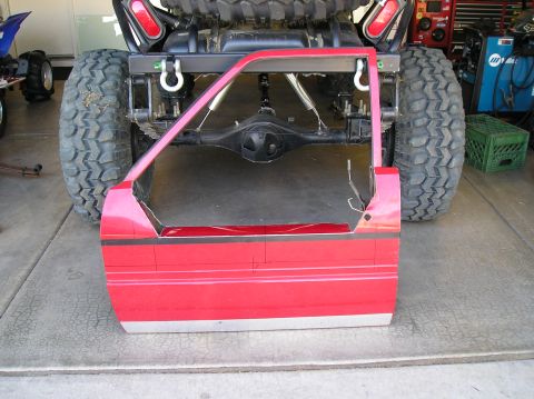 1986 Toyota Hilux - A custom-cut vehicle door is prepared for modification, revealing heavy-duty suspension and a large tire.