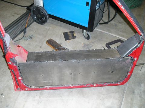 1986 Toyota Hilux - A red vehicle door is being repaired with a new sheet metal panel welded into place.