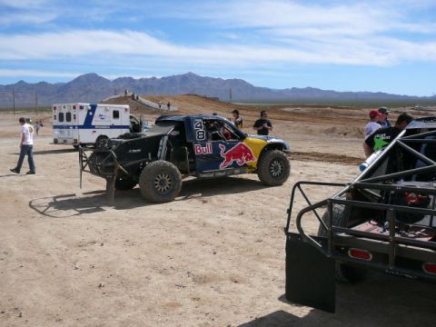 1988 Ford Bronco - A desert race truck with Red Bull sponsorship is parked near an ambulance and other vehicles.