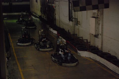 1993 Ford Probe - Multiple go-karts are seen racing on an indoor track with checkered flag and tire barriers.