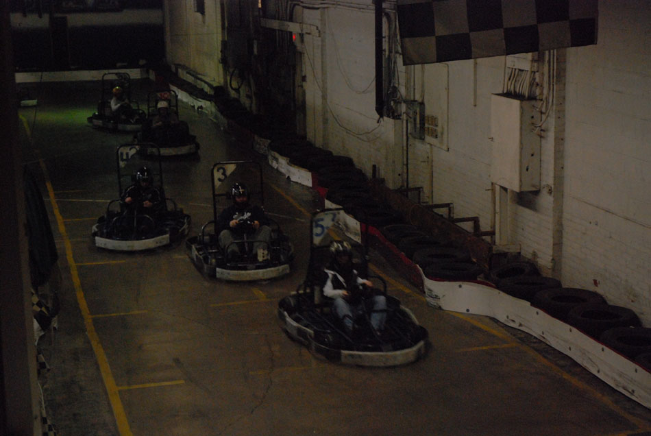 Go-karts racing on an indoor track with numbered signs