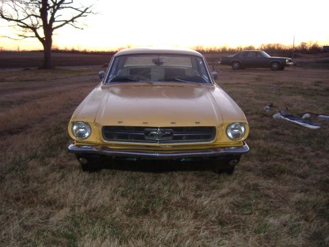1987 Ford Crown Victoria LTD - Front view of a yellow 1965 Ford Mustang with a dark sedan in the background.