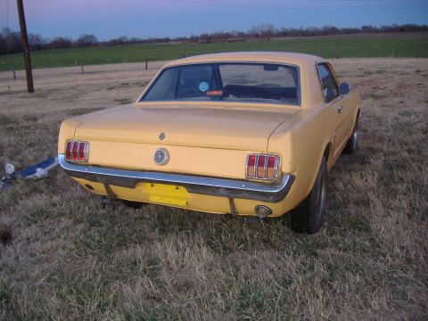 1987 Ford Crown Victoria LTD - Rear view of a vintage yellow Ford Mustang coupe in a field at dusk.
