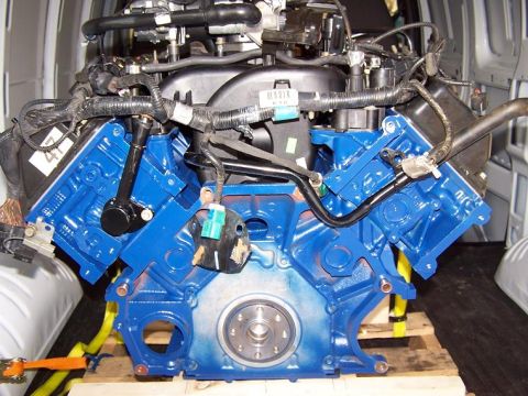2000 Ford Crown Victoria - A freshly painted V8 engine is prepared for installation, resting on a pallet within a vehicle's cargo area.