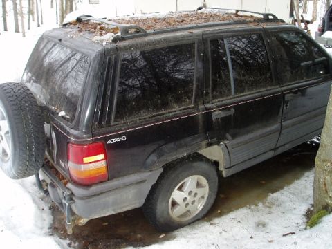 2000 Ford E350 - Rear view of a black Jeep Grand Cherokee with a spare tire on the back, parked in a snowy area.