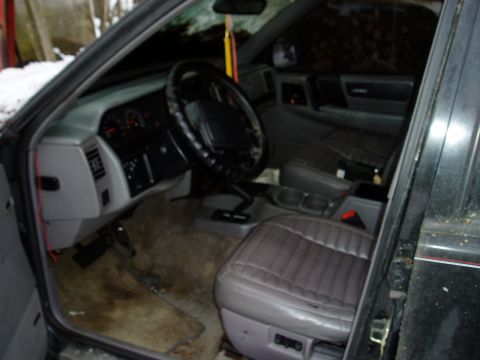 2000 Ford E350 - The interior of a vehicle shows gray seats and dashboard with visible water stains on the floor.