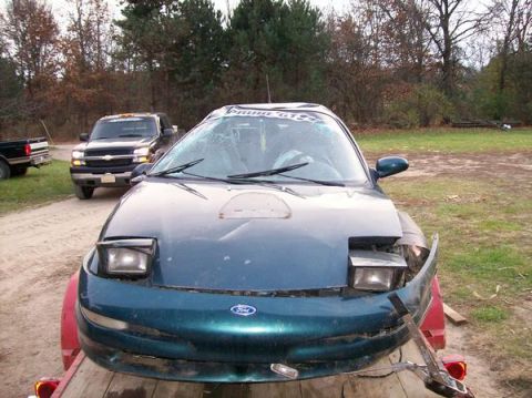 1996 Ford Probe - Front view of a damaged 1996 Ford Probe on a trailer, with a pickup truck in the background.