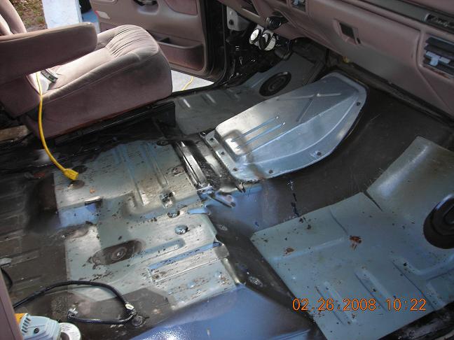 interior floor of a vehicle with seats removed, showing exposed metal and some tools